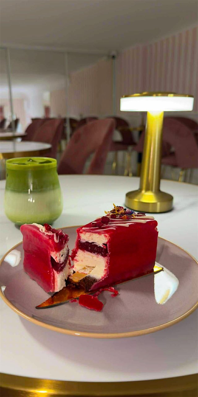 Przekrojona monoporcja w czerwonej glazurze na talerzu w kawiarni, obok matcha latte